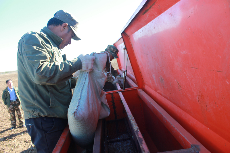 图为统营队工作人员正在添加冬黑麦种子 张萌摄.JPG