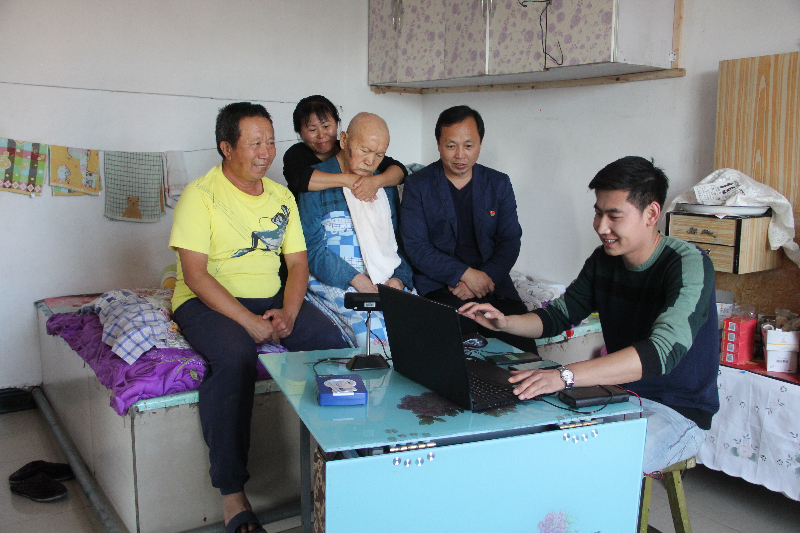 宜里农场劳资部门把不忘初心牢记使命活动主题教育与转变工作作风相结合，变被动为主动，在为离退休人员办理生存认证信息工作中，主动深入一线为瘫痪在床的人员办理，送服务进家庭。图为：劳资部门工作人员为离休老干部赵树林办理业务。（宋丽丽）..JPG